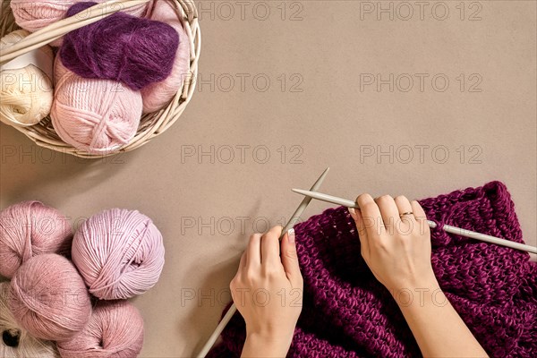 Close-up of female hands knitting wool sweater or plaid lilac color. Top view