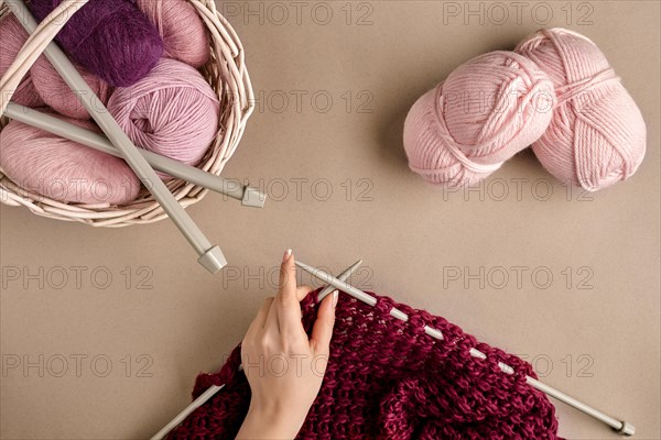 Close-up of female hands knitting wool sweater or plaid lilac color. Top view