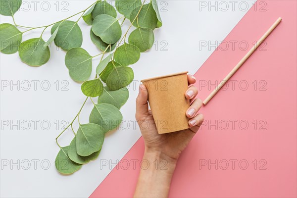 eco natural paper coffee cup, hand and straw flat lay on white and pink background. sustainable lifestyle concept. zero waste, plastic free items