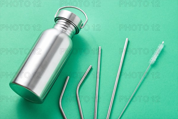 Reusable plastic free items on green background. Top view of aluminun bottle and metal tubes. Zero waste eco friendly concept