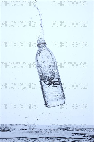 Bottle of water bouncing off surface and splashing