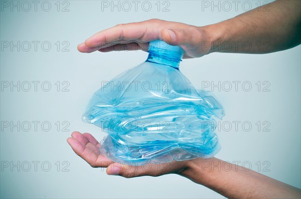 closeup of a young caucasian man smashing a plastic bottle with his hands