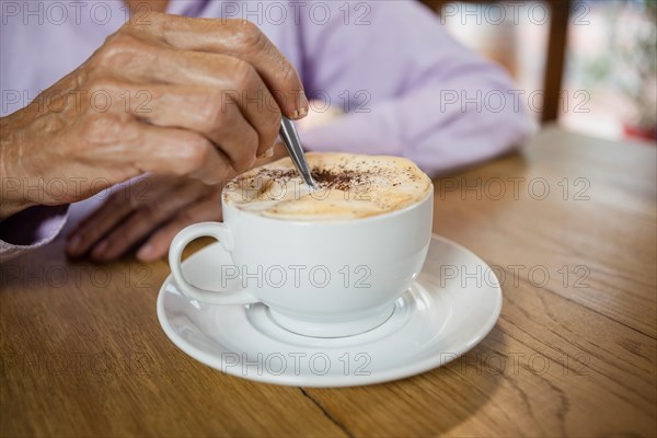 Close up of woman stirring coffee while sitting at table in cafe