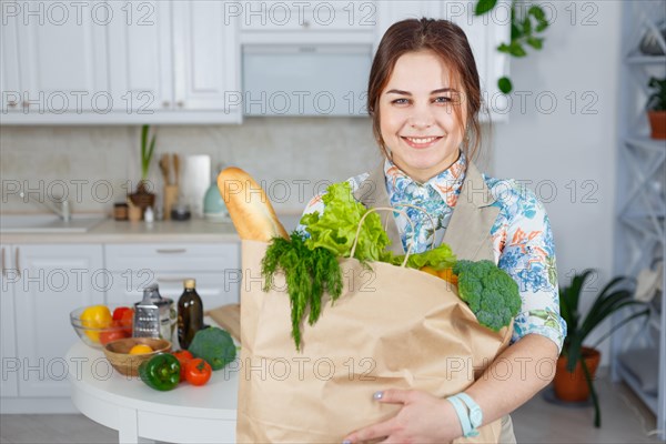 Young woman in the kitchen with a bag of groceries shopping