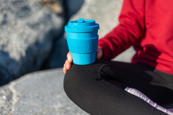 close up of a woman holding a re usable take out coffee mug