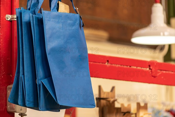 New blue reusable shopping grocery bags at a Market. Alternative to single use plastic bags. Ban on plastics.