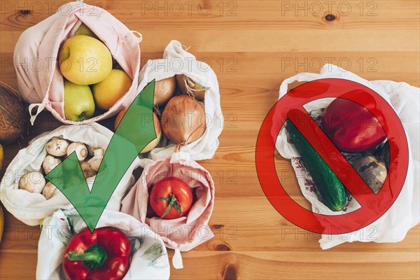 Ban single use plastic. Zero Waste shopping concept. Fresh groceries in reusable eco bags and vegetables in plastic polyethylene bag on wooden table.