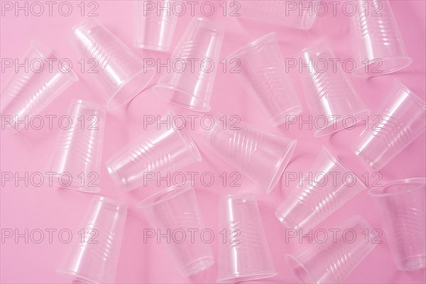 Disposable waste plastic glasses on pink background. Top view