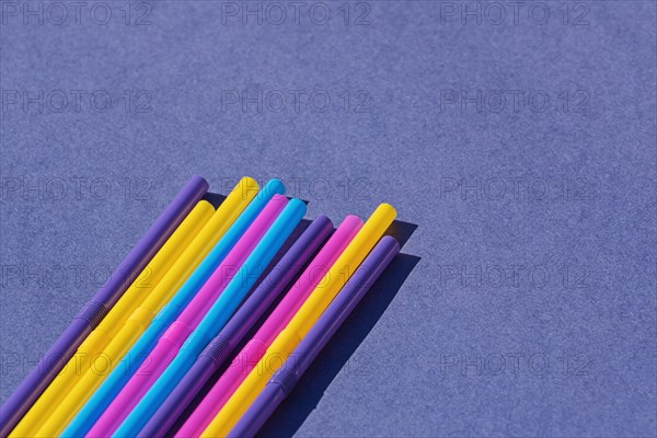 Colored disposable plastic straws on purple background with copy space. Concept of ban on use of plastic tubes in Europe in April 2020