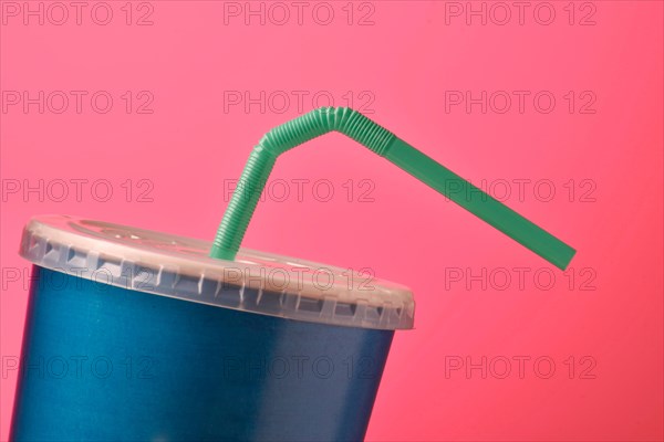 blue plastic tumbler with straw pink background.