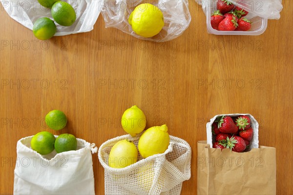 Thin plastic versus cotton grocery bags with fresh fruits on wooden background, zero waste concept.