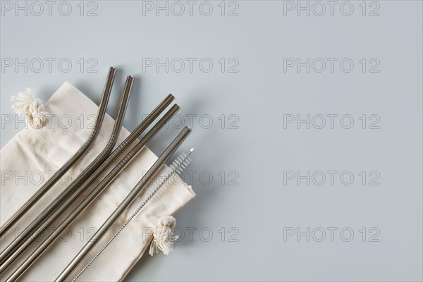 Eco natural metallic straws with cotton bag on pastel grey background. Sustainable lifestyle concept. Zero waste, plastic free. Pollution environment.