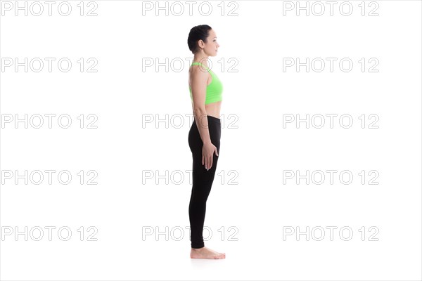 Sporty girl on white background performing basic standing asana tadasana, mountain yoga posture, pose from surya namaskar