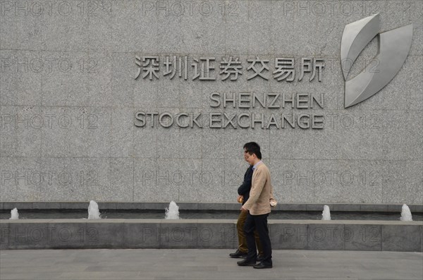 Two men walking by Shenzhen Stock Exchange, China.