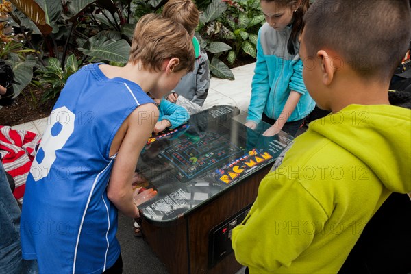 Young children playing the classic Pac-Man video arcade game - USA