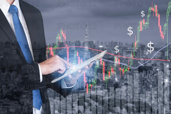 Businessman using digital tablet working with stock market chart in computer screen over the stock market exchange on tokyo city