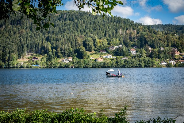 Man in fishing boat on a peaceful Lac de GÃ©rardmer, France, Europe