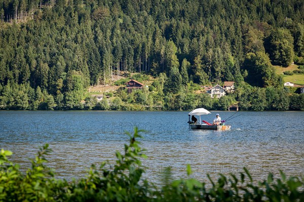 Man in fishing boat on a peaceful Lac de GÃ©rardmer, France, Europe