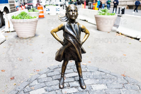 New York City, USA - October 30, 2017: Wall Street stock exchange The Fearless Girl statue facing Charging Bull metal in NYC Manhattan lower financial