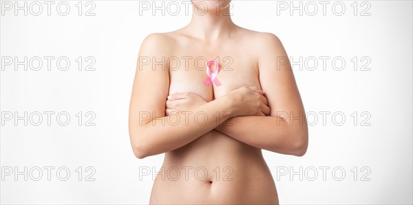 Naked woman covers her breasts with her hands. Pink ribbon over the breast. Breast cancer symbol