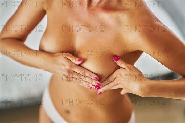 Caucasian woman check her breast for cancer