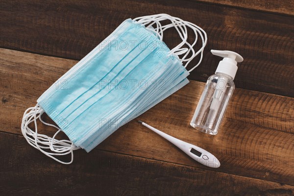 Hand Sanitizer, Surgical Mask and Digital Thermometer on a wooden table. Concept of pandemic, Pollution and health care