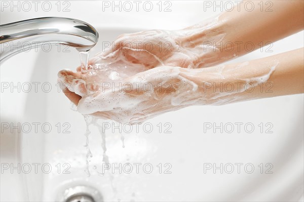 Hand Washing in white sink. Water flows from a faucet at soapy female hands. Covid-19 coronavirus protective measure.