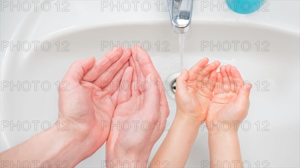 Washing Hands background. Hands of child and adult near the sink. Protection from coronavirus COVID-19 disease. Wash hands concept. Hands of father