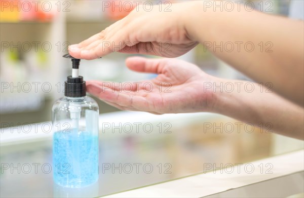 Female hand pressing alcohol gel or sanitizer pump bottle for washing hand in hospital or public area. Coronavirus infection or COVID-19 outbreak prev