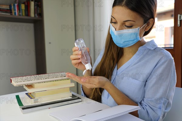 COVID-19 Pandemic Coronavirus Woman with Surgical Mask Studying from Home using Alcohol Gel from Dispenser against 2019-nCoV. Home Working, Auto Quara