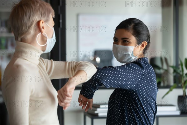 Diverse colleagues greeting touching elbows in office