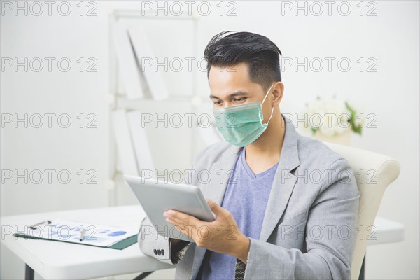 asian man using tablet pc working from home wear face masks