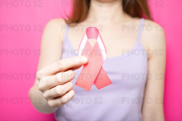 The girl is holding a pink ribbon in her hands. Breast Cancer Symbol