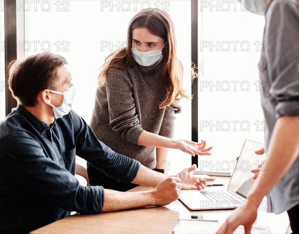 employees in protective masks discussing online information