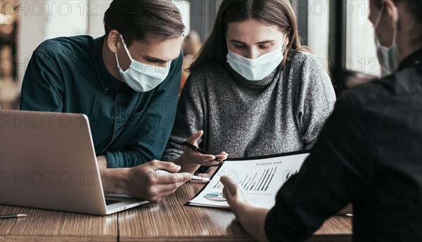 business colleagues in protective masks sitting at the office Desk.