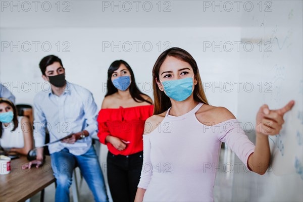 Latin woman working in business office or coworking while wearing medical face mask for social distancing in new normal situation protecting and preve