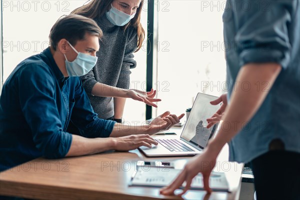 employees in protective masks discussing online information