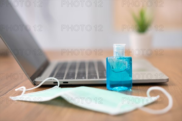 Coronavirus disease (COVID-19) prevention set, hand sanitizer gel, and masks beside laptop for prevention or antibacterial hygiene at the office durin