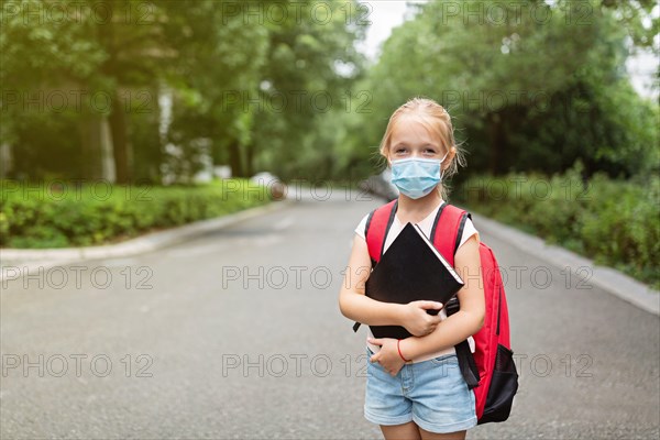 School child wearing face mask during coronavirus pandemic outbreak. Blonde girl going back to school after covid-19 quarantine and lockdown. Kid in