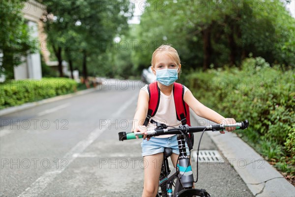 School child wearing face mask during coronavirus pandemic outbreak. Blonde girl going back to school after covid-19 quarantine and lockdown. Kid in