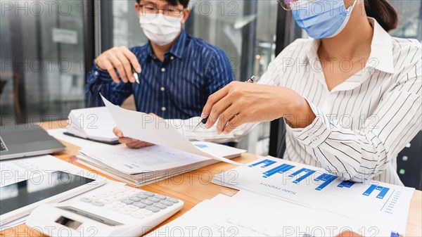 Group of Teamwork Asian business People Wearing Protective face Mask In Office During Pandemic coronavirus COVID-19, New Normal and Social distancing