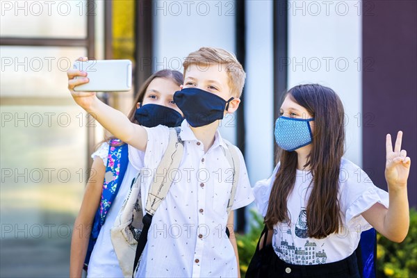 School children wearing protective face masks while taking selfie at school reopening