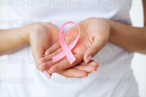 Woman using pink ribbon to support breast cancer cause or AIDS