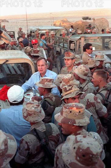 US President George Bush leans on the hood of a Humvee as he talks to Marines during a Thanksgiving Day visit to a desert encampment November 22, 1990 in Saudi Arabia. The President is visiting U.S. troops in Saudi Arabia for Operation Desert Shield.