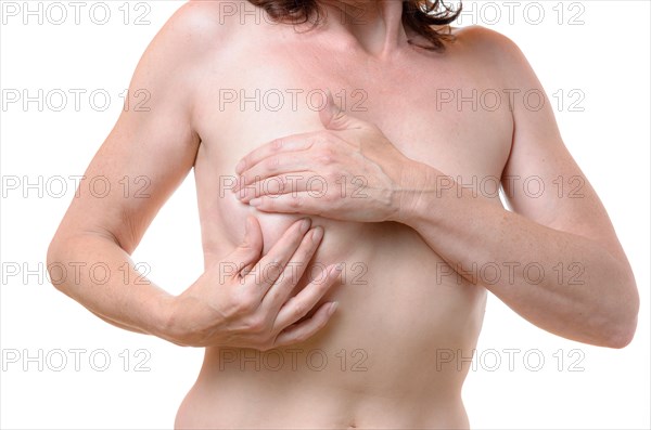 Naked middle-aged woman checking her breast for lumps as a precursor to cancer palpating the tissue between her fingers, close u