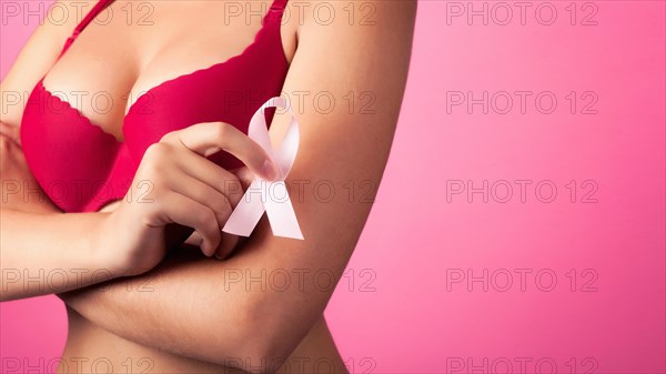 Woman with Big beautiful Breasts won Cancer. Close-up photo of a female breast in a red bra with Pink Ribbon. Background. healthcare and medicine conc