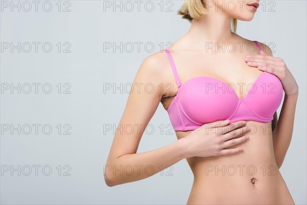 cropped view of woman in pink bra isolated on grey, breast cancer concept