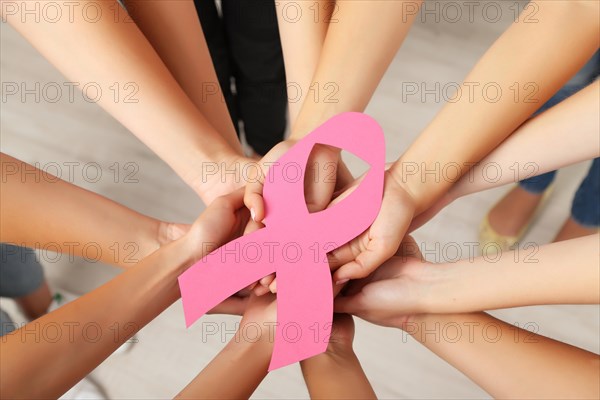 Women hands joined in circle holding breast cancer symbol