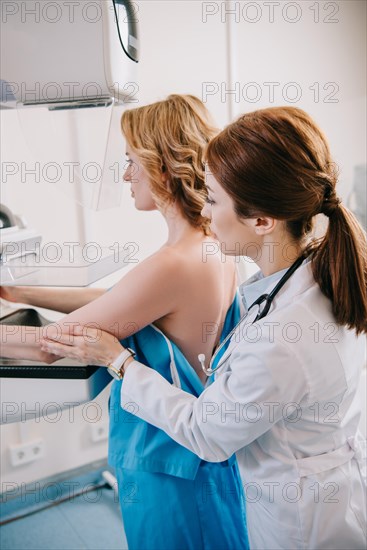 attentive radiologist preparing woman for mammography test on x-ray machine