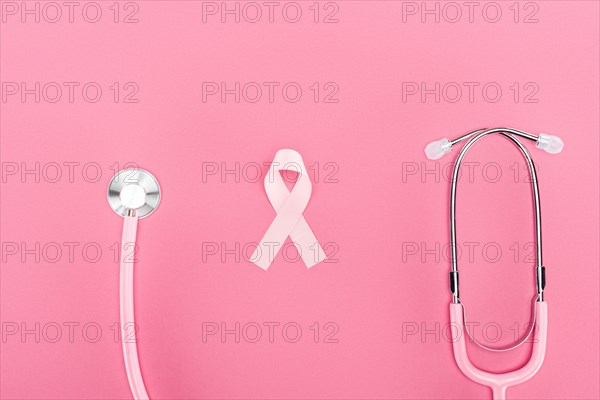 top view of stethoscope and pink breast cancer symbol on pink background